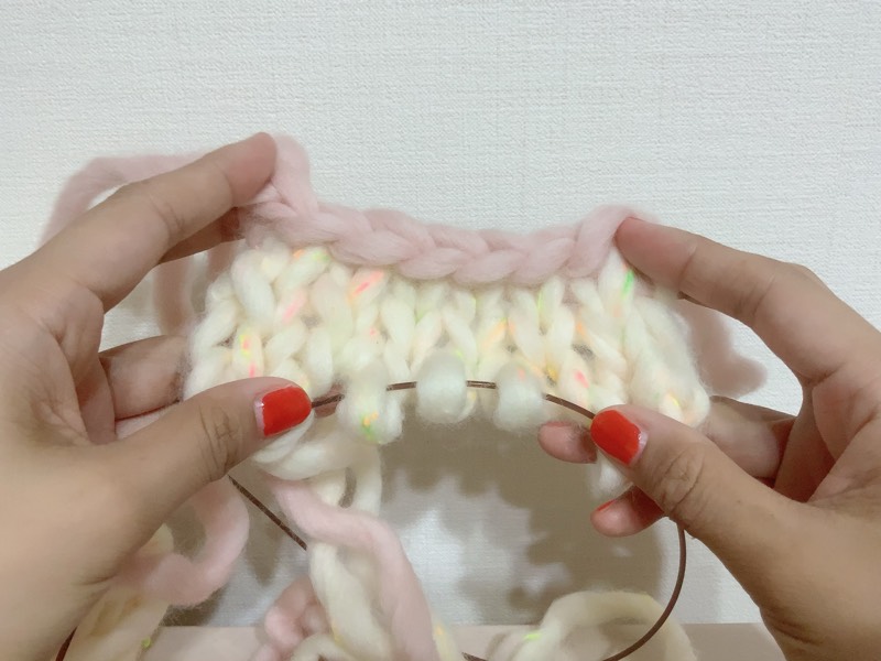白とピンクの毛糸　手　別鎖から編んでひっくり返したところ